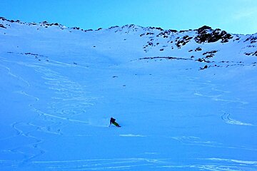 A person skiing down a snowy slope with mountains in the background