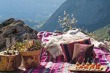A picnic blanket with a bottle of champagne and a basket of flowers