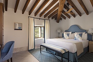 A bedroom with a blue headboard and white sheets