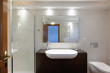 A bathroom with a sink and toilet and a large mirror