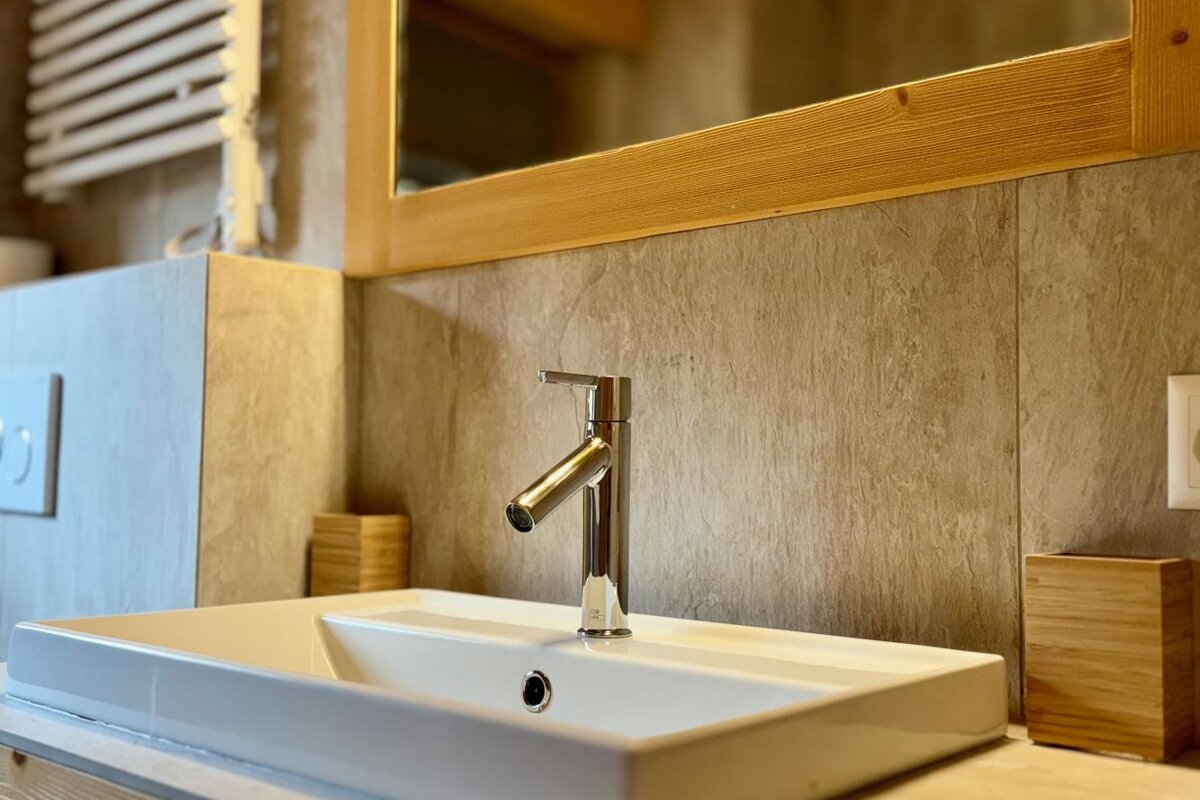 A bathroom sink with a wooden mirror above it