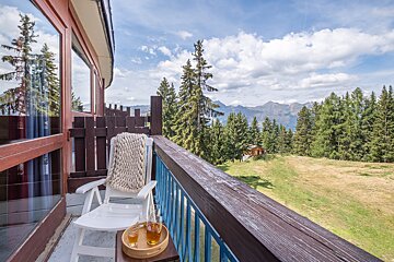 A balcony with a rocking chair and a tray of tea