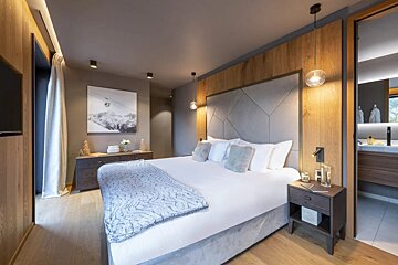 A bedroom with a large bed and a painting on the wall