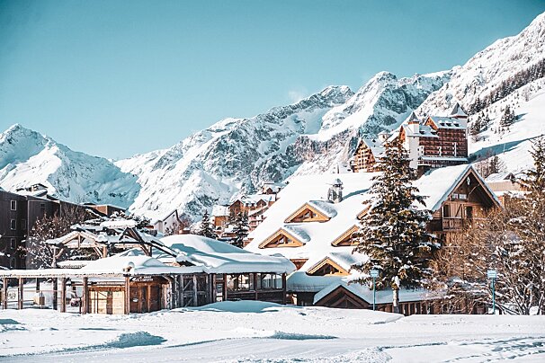 Snow covered buildings in a ski resort with mountains in the background