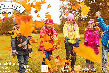 A group of children are throwing leaves in the air and the words kids clothes are on the bottom