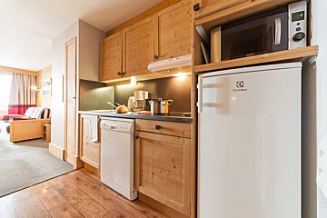A white electrolux refrigerator sits next to a microwave