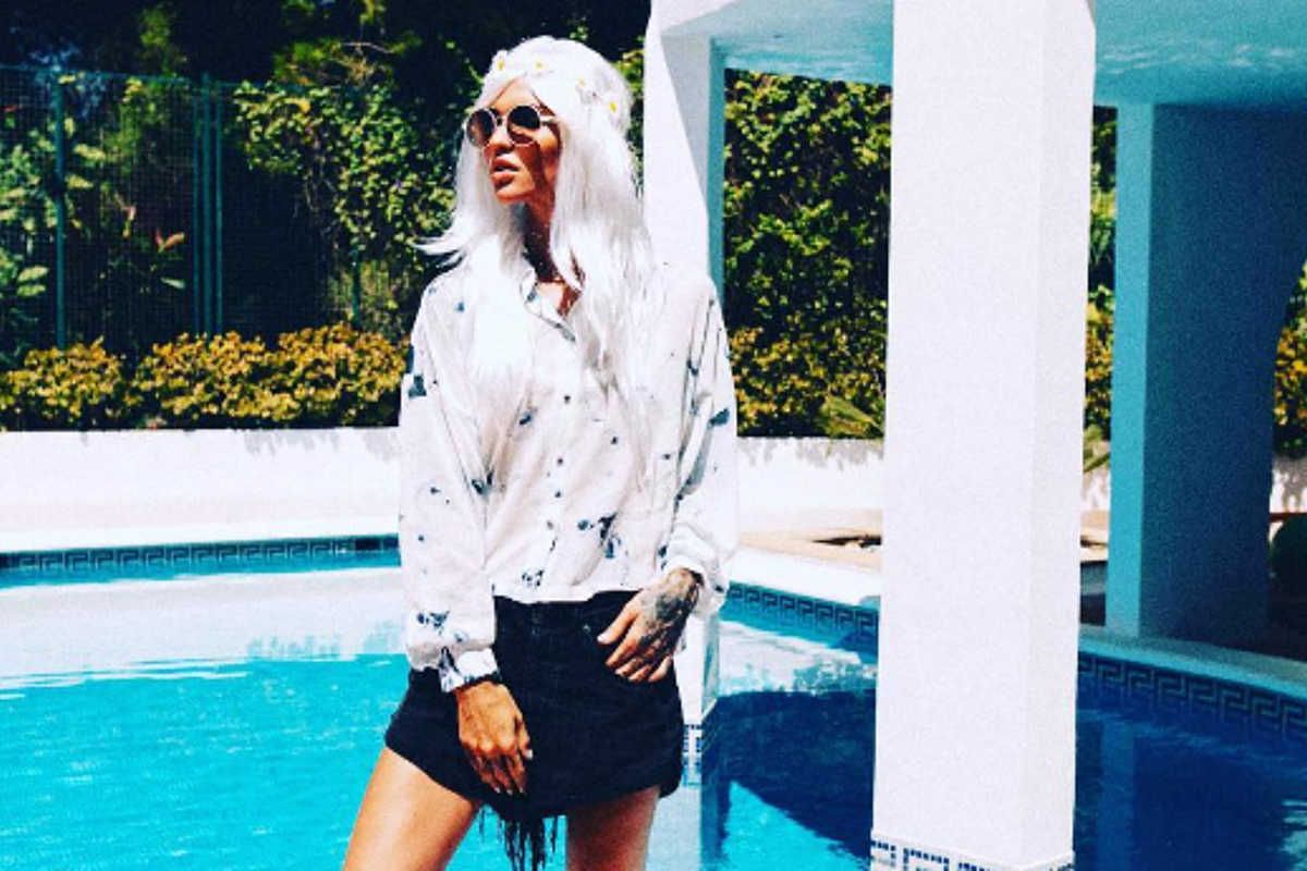 A woman with white hair is standing in front of a pool