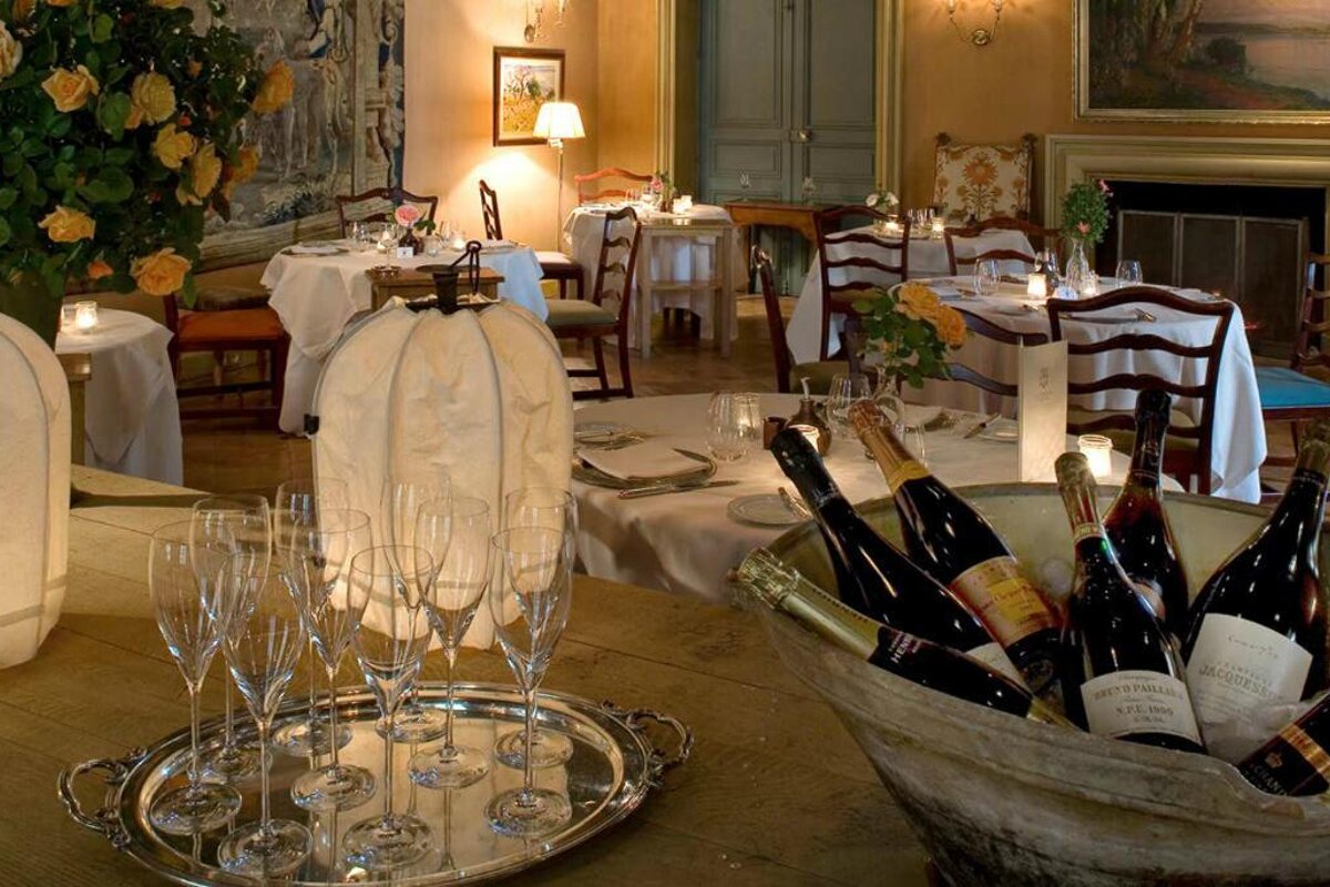 image of the inside of a grand dining room with champagne in a bucket at the front and tables laid for service