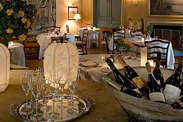 image of the inside of a grand dining room with champagne in a bucket at the front and tables laid for service
