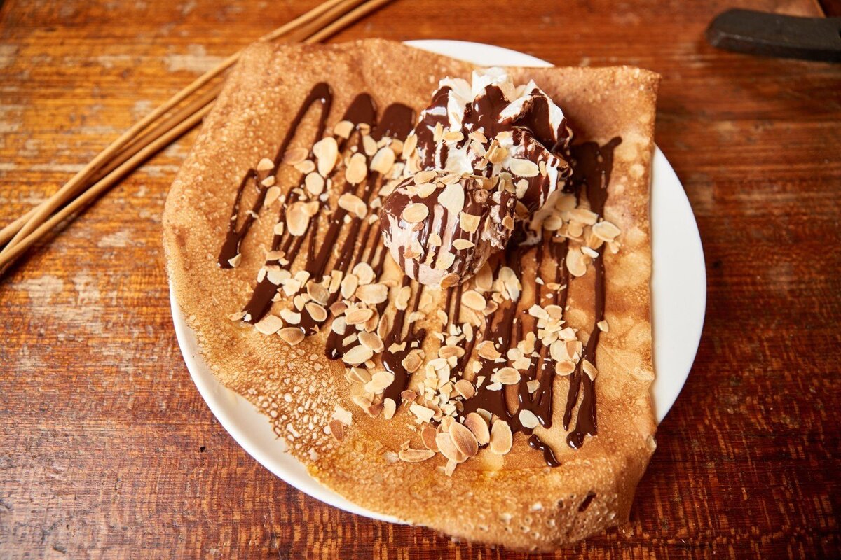 A pancake with chocolate sauce and nuts on it