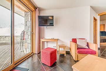 A living room with a red chair and a flat screen tv