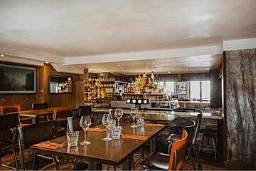 A restaurant with tables and chairs and a bar in the background