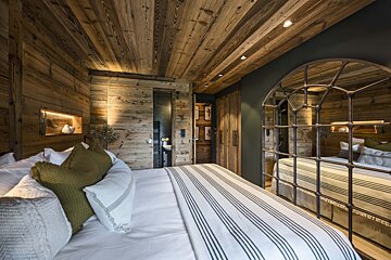 A bedroom with wooden walls and a large mirror