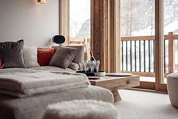 A bottle of champagne sits on a wooden table in a living room