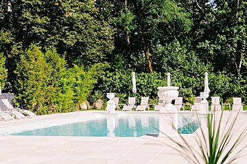 A large swimming pool surrounded by chairs and umbrellas