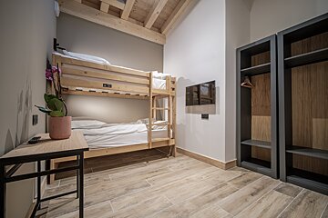 A bunk bed in a room with a tv on the wall