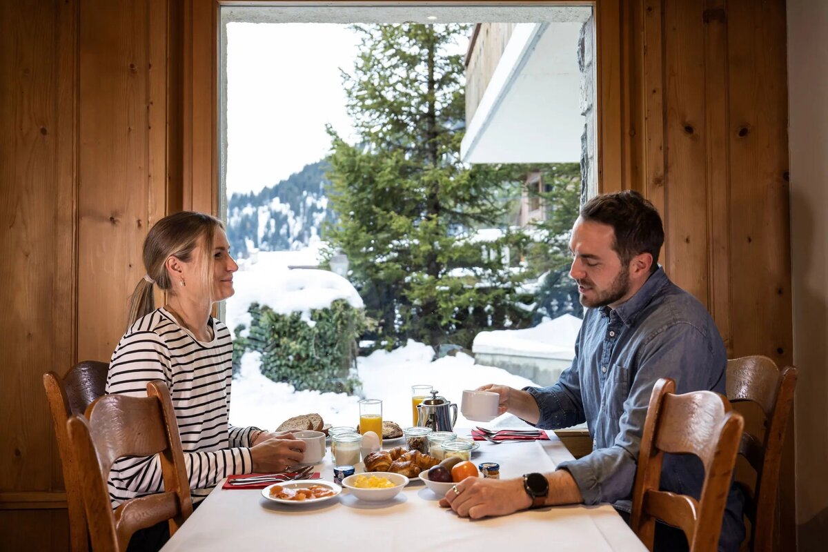 A man and a woman are sitting at a table eating food