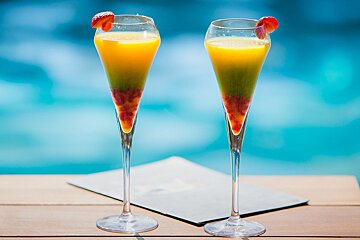 Two glasses of orange juice with strawberries on top