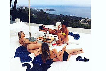 A group of women laying on a couch with a view of the ocean