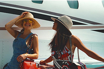 Two women wearing hats and sunglasses are standing next to each other
