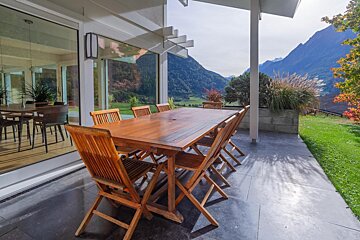 A table and chairs on a patio with mountains in the background