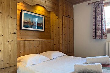 A bedroom with a picture on the wall above the bed