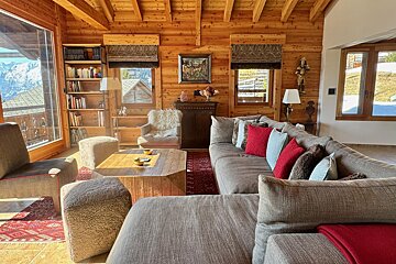 A living room in a log cabin with a couch and chairs