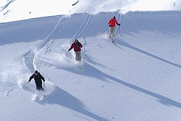 Three people skiing down a snow covered slope
