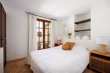 A bedroom with a large bed and two lamps