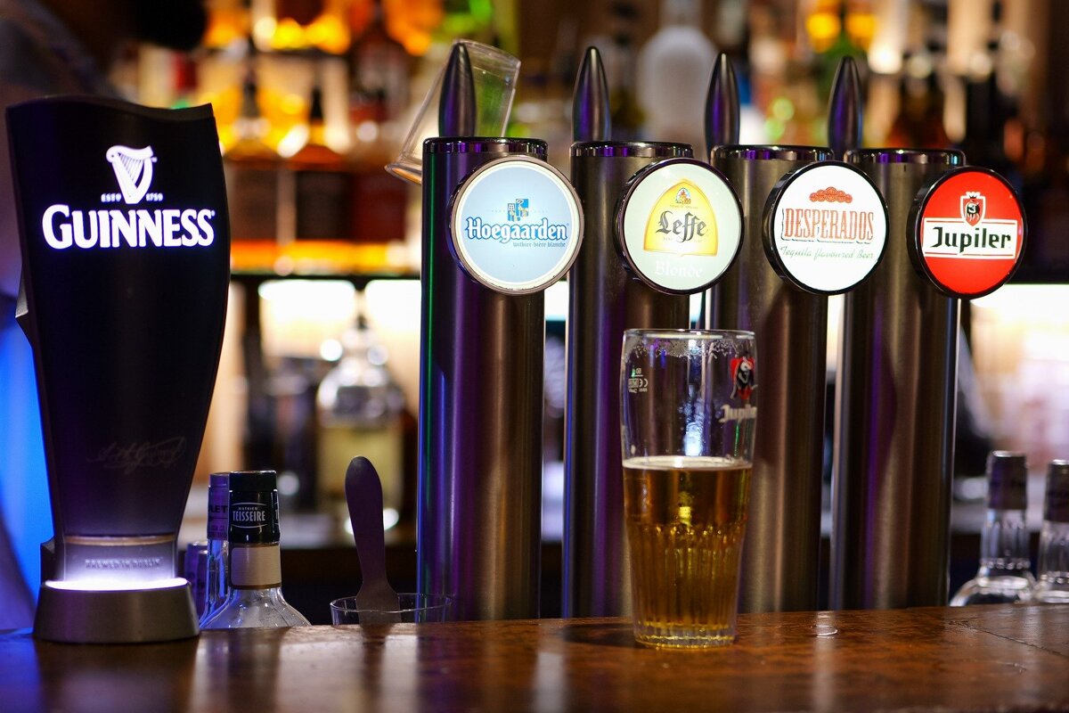 A guinness beer bottle sits next to a glass of beer