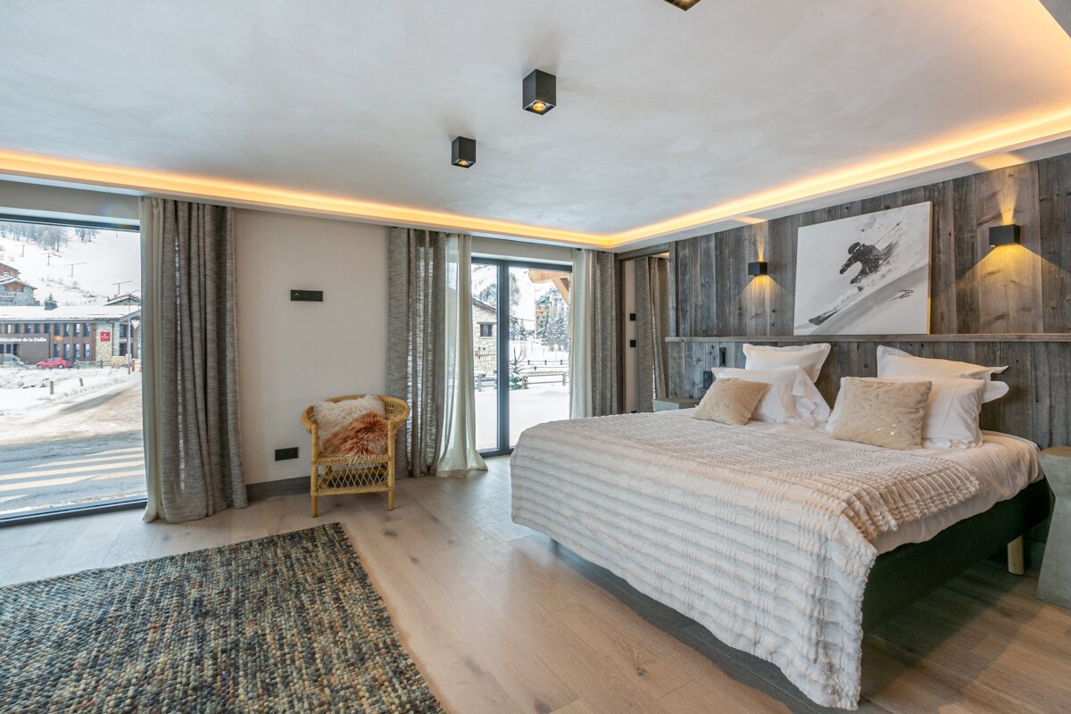 A bedroom with a large bed and a chair