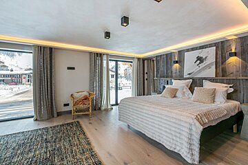 A bedroom with a large bed and a chair