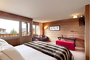A bedroom with a large bed and a red ottoman