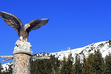 A statue of an eagle sitting on top of a tree trunk