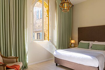 A bedroom with a bed a chair and a window