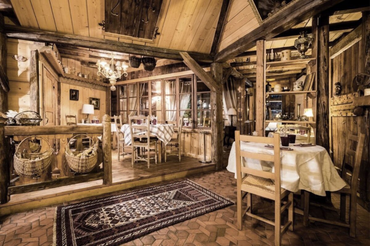 A wooden room with tables and chairs and a rug