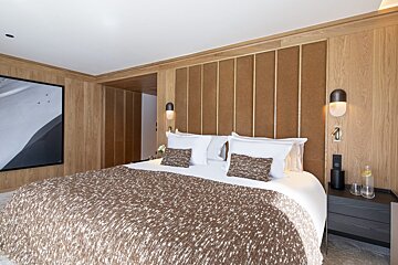 A bedroom with a painting on the wall above the bed