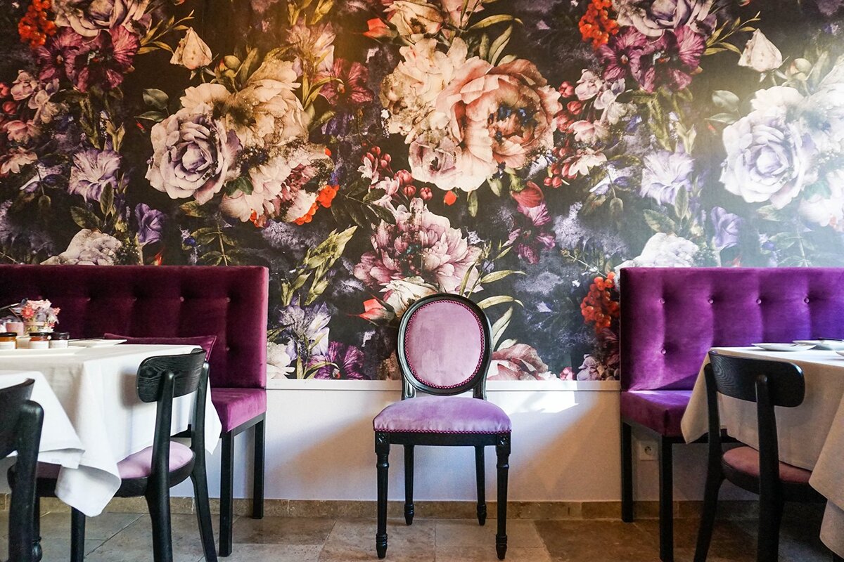 A dining room with purple chairs and a floral wallpaper