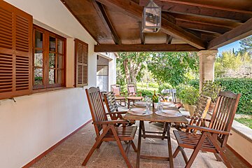A table and chairs on a porch with a lantern hanging from the ceiling