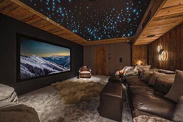A room with a couch and a large screen with mountains on it