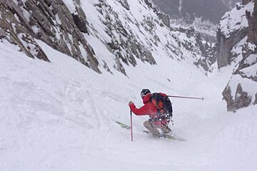 A person in a red jacket skiing down a snow covered slope