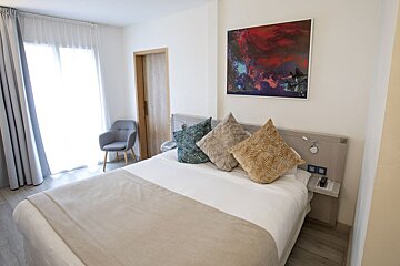 A hotel room with a bed and a painting on the wall