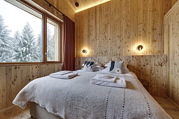 A bedroom with wooden walls and a large bed
