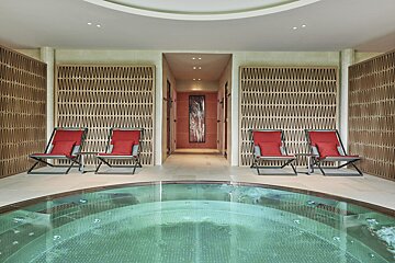 A swimming pool surrounded by chairs and a wall with a picture on it