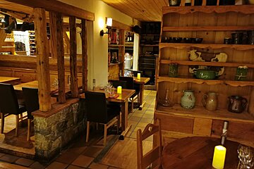 A restaurant with tables and chairs and a shelf with pots and pitchers on it