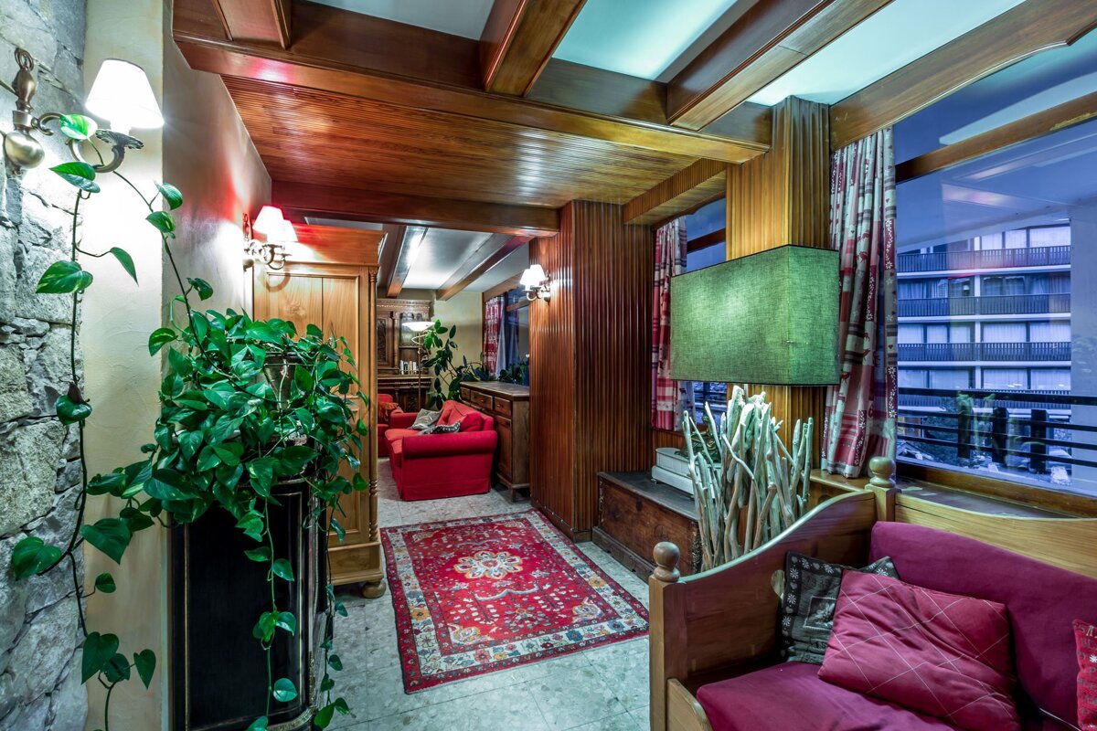 A living room with a red couch and a green lamp