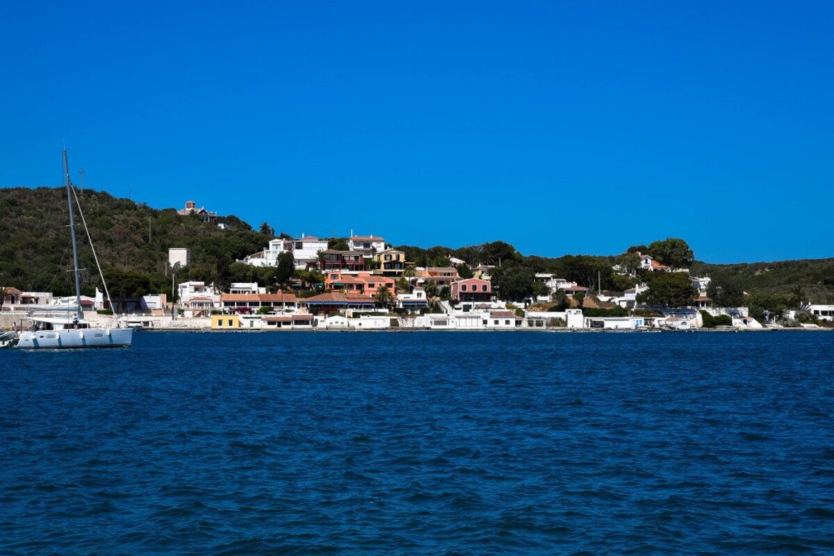 A white boat is in the water near a small town