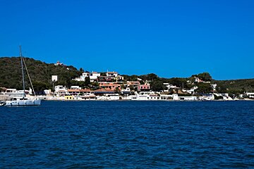A white boat is in the water near a small town