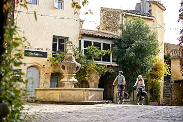 Two people riding bicycles in front of a restaurant
