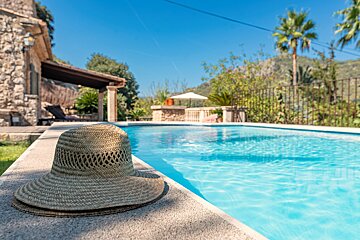A straw hat sits on the edge of a swimming pool